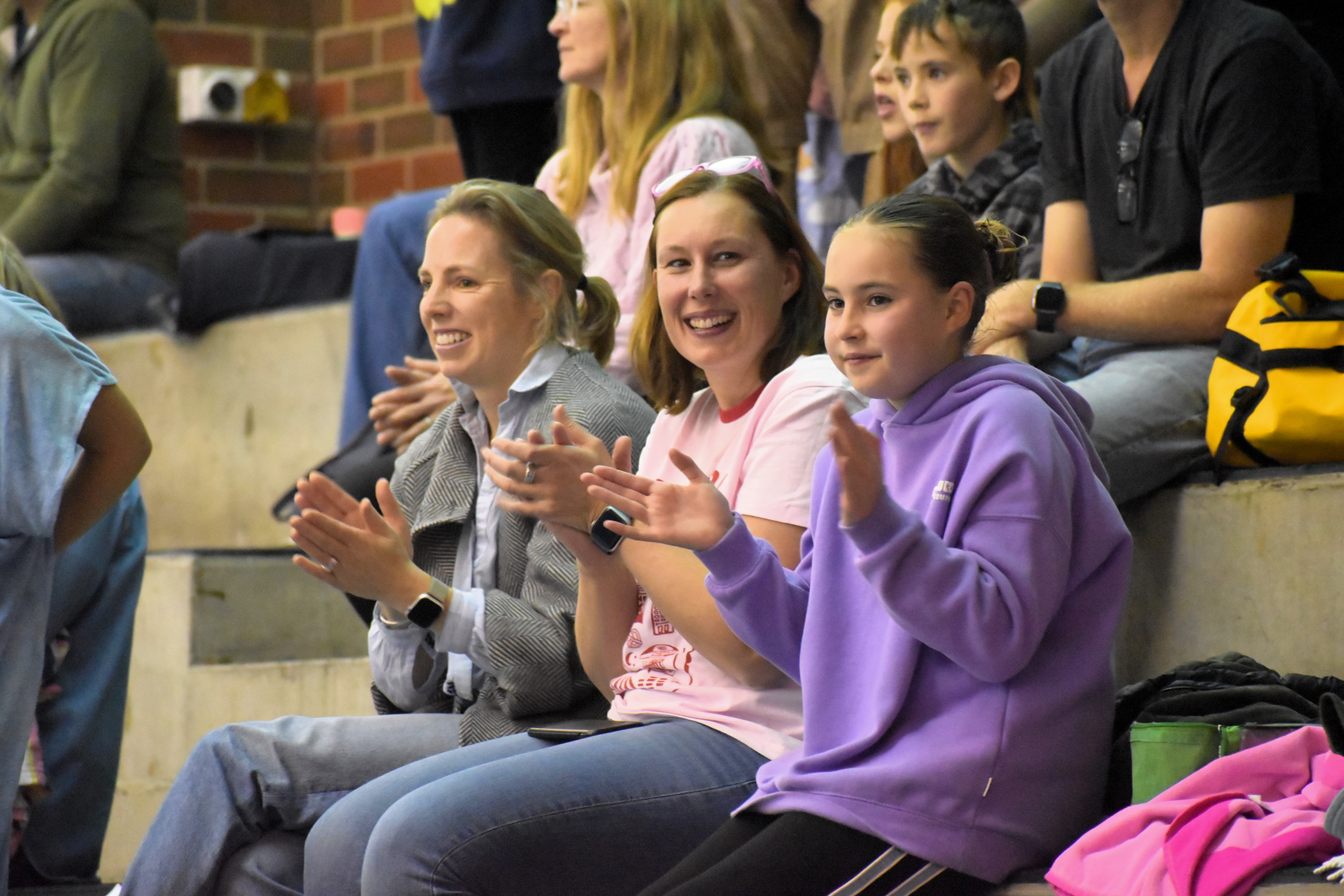 Audience members clapping and smiling in support of student swimmers at The Geelong College swimming carnival.